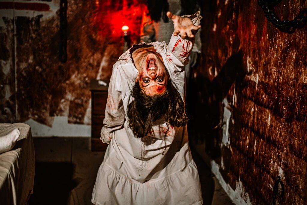A woman in a white dress with blood stains, bending her back